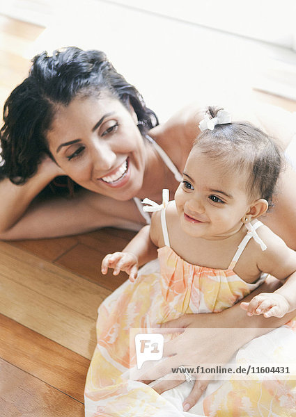 Mixed Race mother laying on floor holding baby daughter