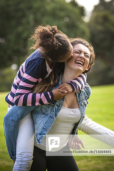 Portrait of laughing girl carrying sister piggyback
