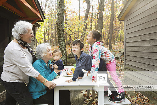 Großmütter spielen mit Enkelkindern am Frühstückstisch im Freien