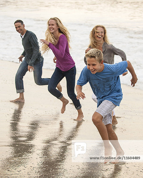 Lächelnde Familie beim Laufen am Strand