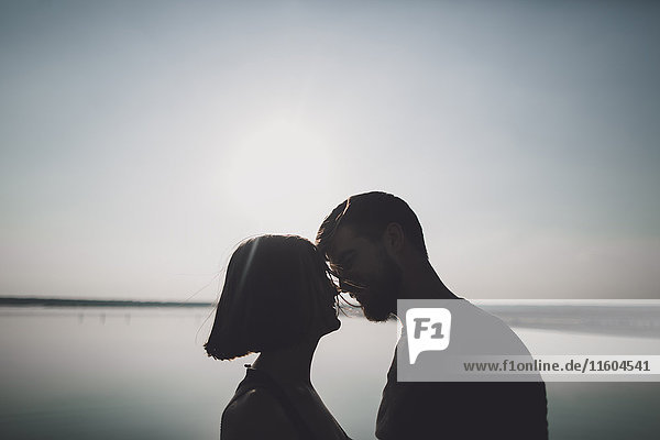 Silhouette of Caucasian couple face to face at lake