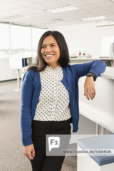Smiling Pacific Islander woman standing in office