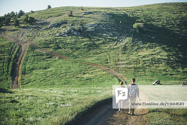 Kaukasisches Paar geht auf einem Pfad in Richtung Hügel