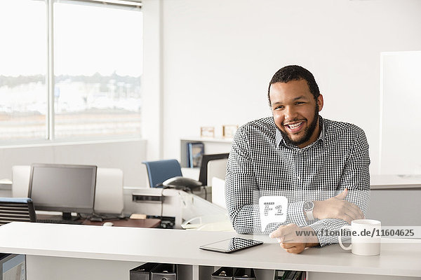 Smiling Mixed Race man leaning in office