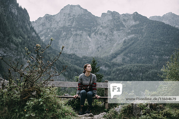 Kaukasische Frau sitzt auf einer Bank in den Bergen