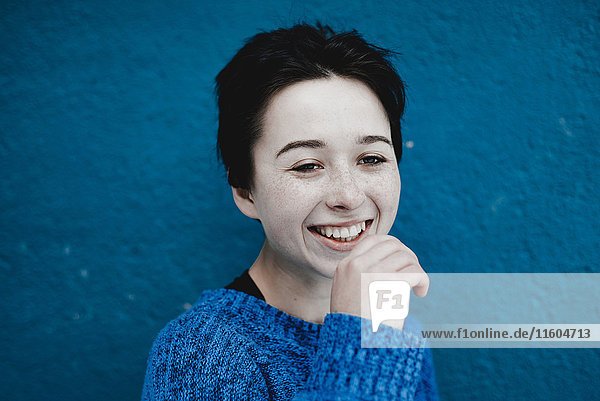 Smiling Caucasian woman near blue wall
