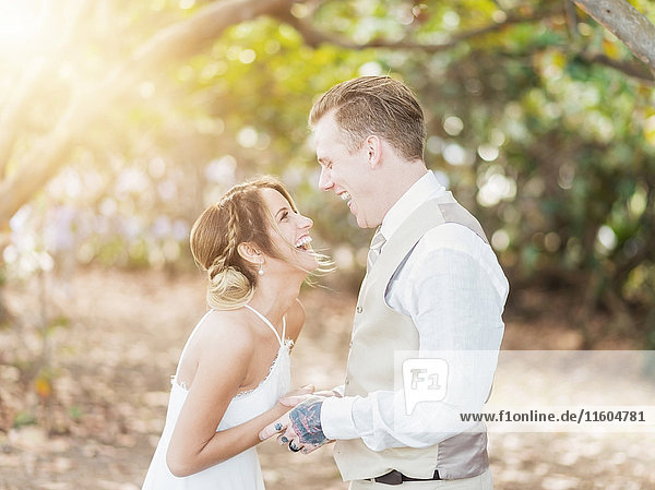 Caucasian bride and groom laughing outdoors