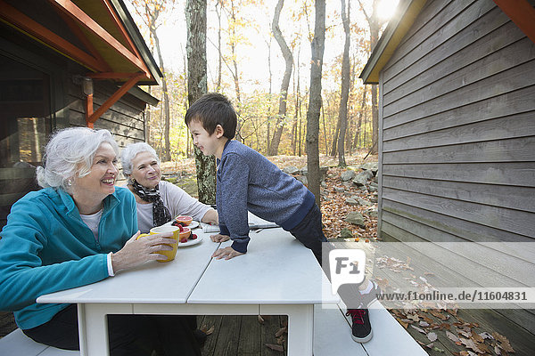 Grandmothers enjoying breakfast outdoors near cabin with grandson