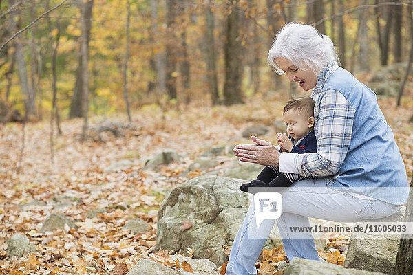 Großmutter spielt mit ihrem kleinen Enkel im Herbst