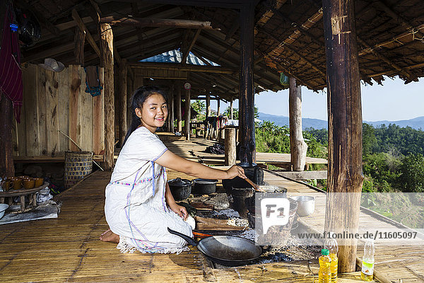 Smiling Asian woman cooking on patio outdoors