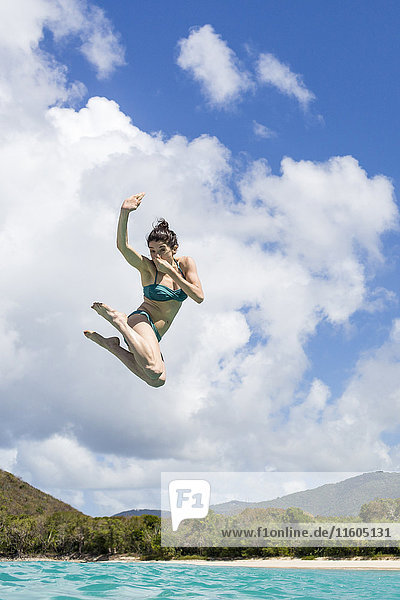 Caucasian woman jumping into tropical ocean