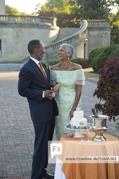 Schwarzes Paar lachend in der Nähe der Hochzeitstorte