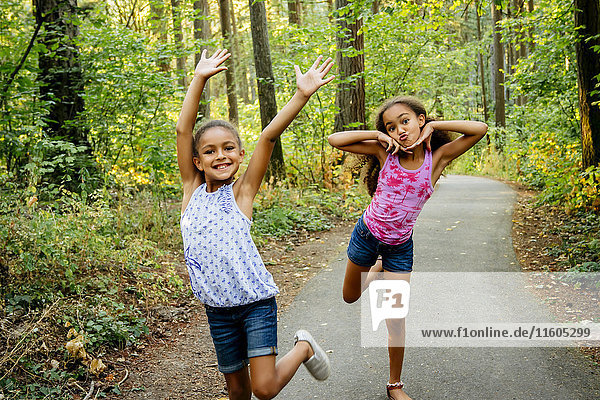 Mixed Race Schwestern mit Spaß posieren auf Waldweg