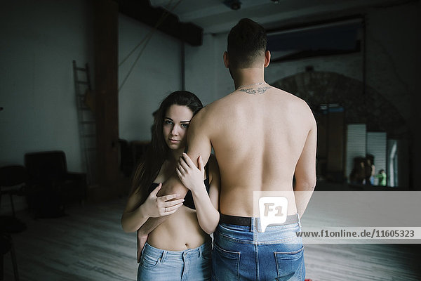 Kaukasische Frau umarmt den Arm eines Mannes mit nacktem Rücken