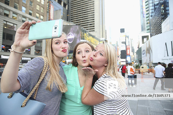 Puckering kaukasischen Frauen posieren für Handy-Selfie in der Stadt