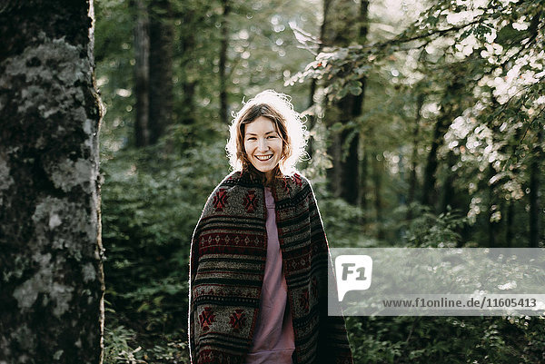 Lächelnde kaukasische Frau mit Kopftuch im Wald