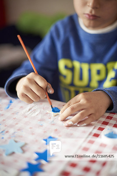 Hispanic boy painting stars at table