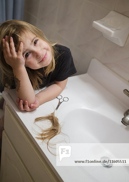 Caucasian girl cutting her hair in bathroom