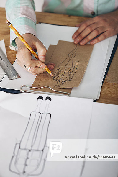 High angle view of female designer drawing sketch on paper at studio