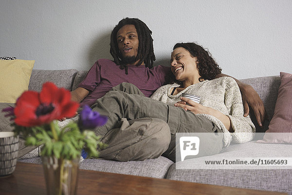 Cheerful multi-ethnic couple relaxing on sofa at home