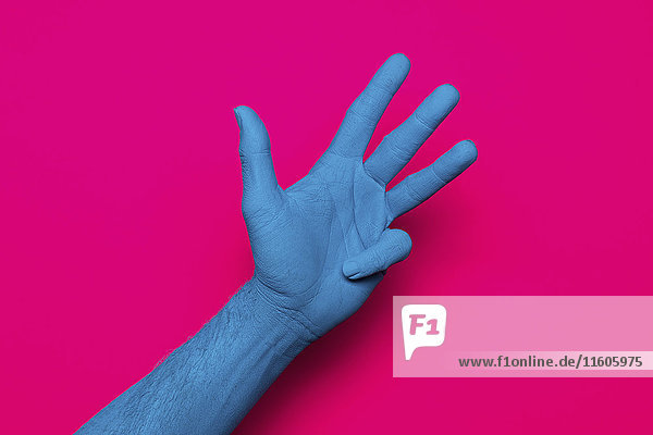 Nahaufnahme der blau bemalten Hand auf rosa Hintergrund
