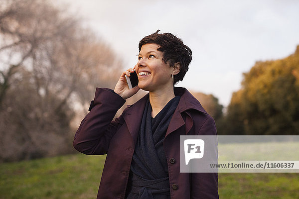 Fröhliche erwachsene Frau mit Smartphone auf dem Feld