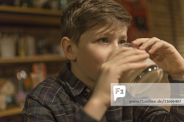 Junge schaut weg  während er zu Hause Milch trinkt.