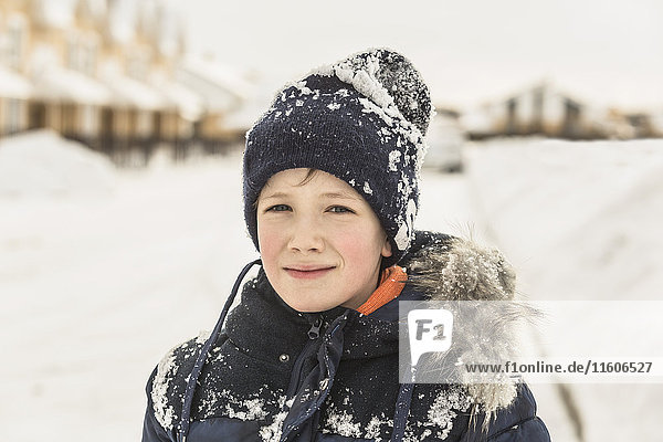 Portrait of confident boy in winter wear covered with snow
