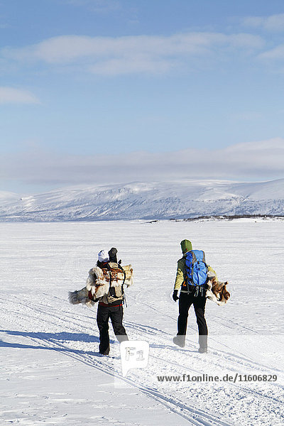 People carrying ice fishing equipment