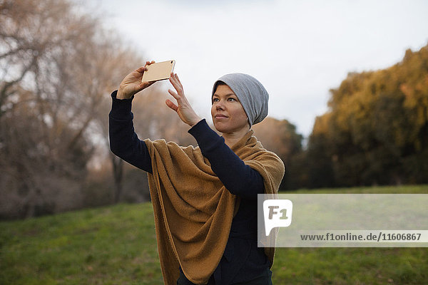 Mittlere erwachsene Frau beim Fotografieren durch Smartphone auf dem Feld gegen den Himmel