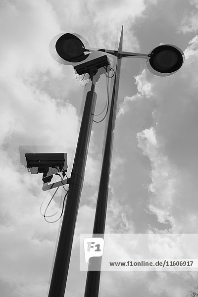 Mehrschichtiges Bild von Überwachungskameras und Straßenleuchten gegen bewölkten Himmel