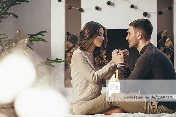 Romantic couple having coffee while sitting at home during Christmas