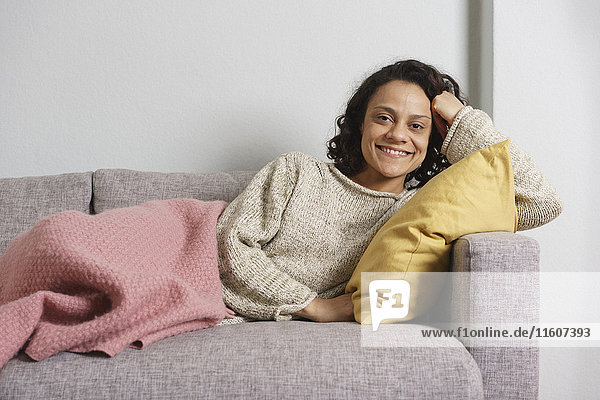 Portrait of happy woman relaxing on sofa at home