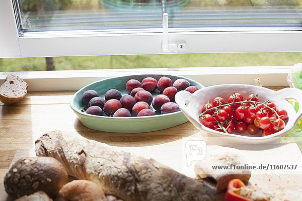 Close-up of fruits and bread on table by window