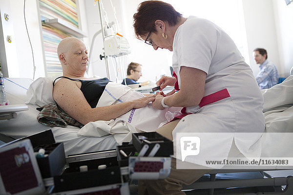 Reportage in der onkologischen Abteilung einer Tagesklinik in Frankreich. Die Hilfskrankenschwester Marie-Cécile arbeitet hier drei Tage in der Woche als Krankenhauskosmetikerin. Sie bietet krebskranken Frauen Schönheitsbehandlungen und Lösungen zur Bewältigung der Nebenwirkungen von Krebsbehandlungen an. Diese Momente eignen sich gut für persönliche Gespräche. Sie gibt einer Patientin eine Schönheitsbehandlung während einer Chemotherapie.