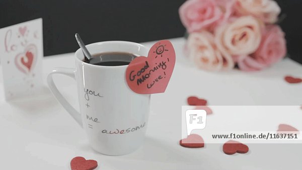 Kaffeetasse mit herzförmigem Aufkleber  Herzen und Blumen auf Tisch 4