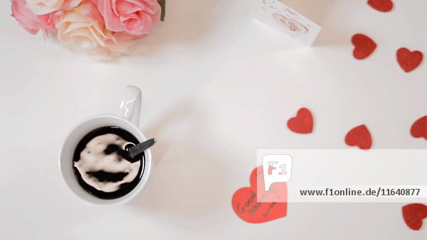 Wirbelnder Kaffee in einer Tasse mit Herzen und Blumen  hohe Winkelansicht