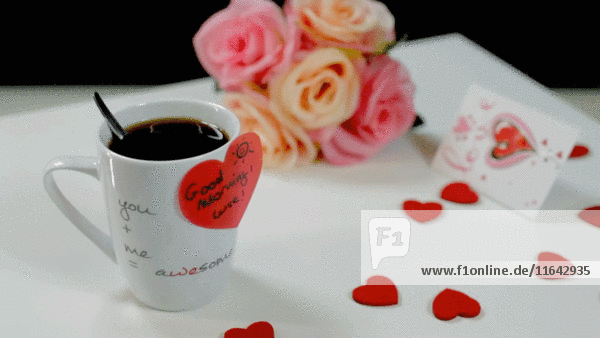 Kaffeetasse mit herzförmigem Aufkleber,  Herzen und Blumen auf Tisch 3
