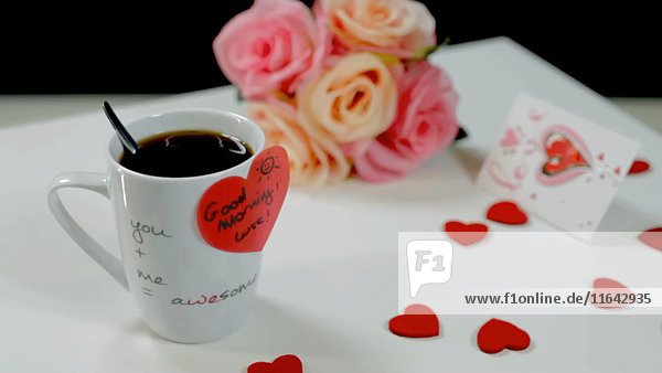 Kaffeetasse mit herzförmigem Aufkleber  Herzen und Blumen auf Tisch 3