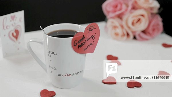 Kaffeetasse mit herzförmigem Aufkleber  Herzen und Blumen auf dem Tisch 5