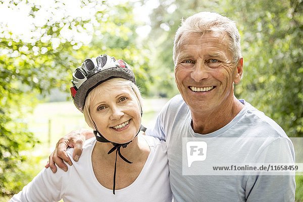 Ältere Frau mit Fahrradhelm  älterer Mann mit Arm um sie.