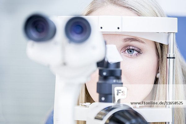 Weibliche Patientin bei einer Augenuntersuchung in einem Optikergeschäft,  Nahaufnahme.