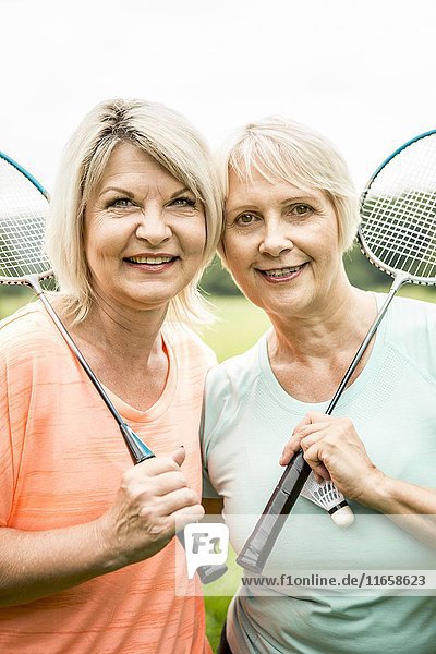 Zwei Frauen halten lächelnd Badmintonschläger.