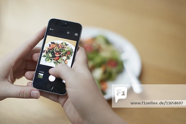 Frau  die mit ihrem Smartphone ein Foto von einem Lebensmittel macht und den Kaloriengehalt überprüft.