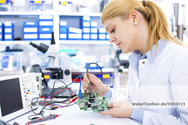 Female engineer soldering a circuit board.