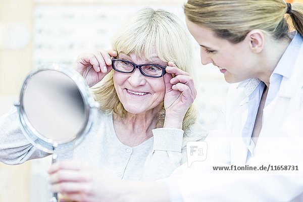 Optometrist counselling senior woman in optometrist's shop.
