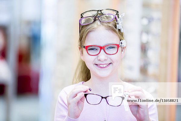 Portrait of girl trying glasses in optometrist's shop.