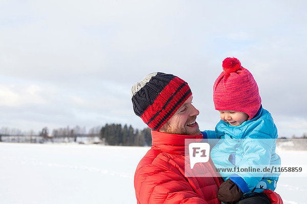 Vater hält kleinen Sohn  in schneebedeckter Landschaft