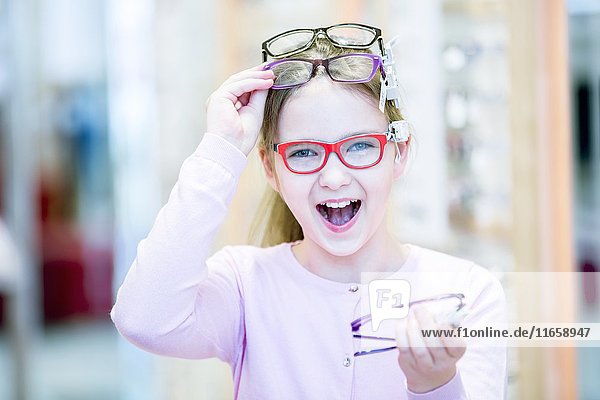 Porträt eines Mädchens  das in einem Optikerladen eine Brille ausprobiert.