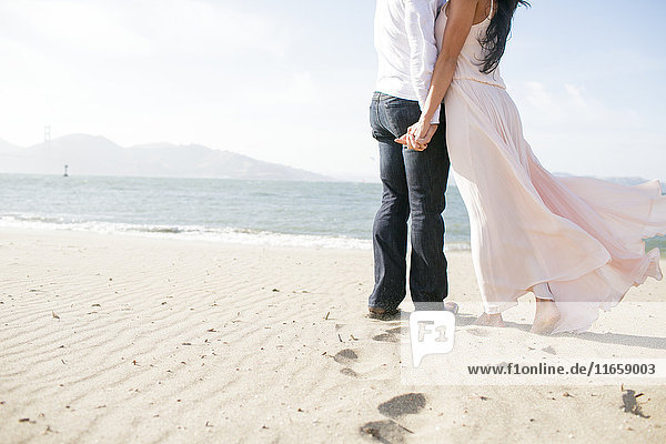 Hals über Kopf ein romantisches Paar Hand in Hand am Strand